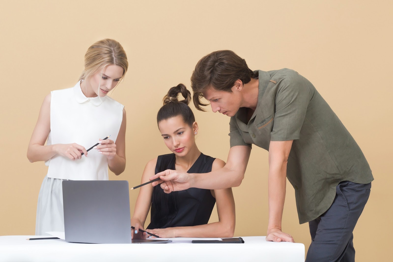 A supervisor talking two young team members through work on a laptop